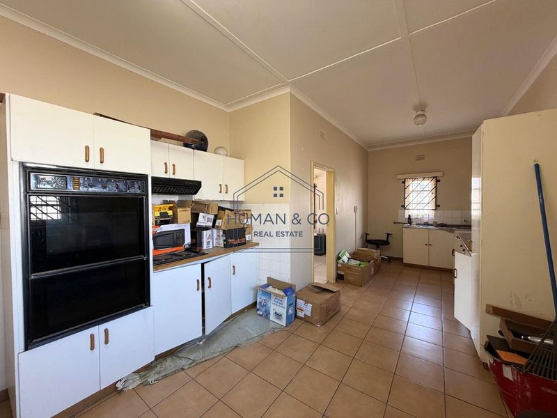 A dated kitchen featuring built-in oven, extractor fan, tiled flooring, and ample cabinetry, offering significant potential for modernization and renovation.