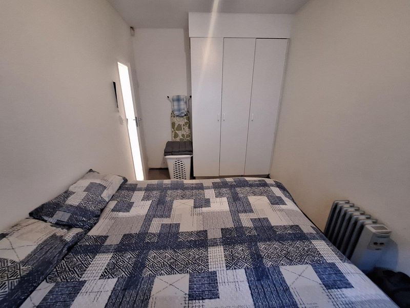A compact bedroom featuring a built-in wardrobe and neutral finishes, providing a functional space for rest.