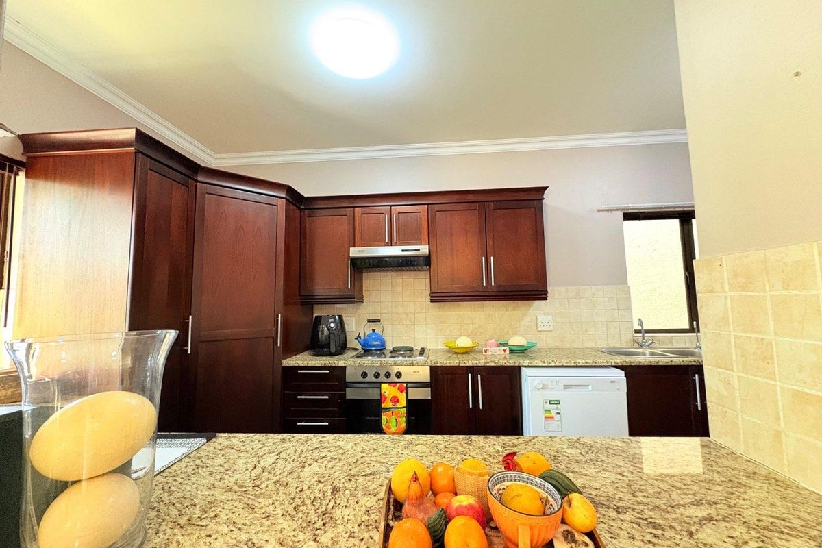 A functional kitchen featuring dark wood cabinetry, granite countertops, a built-in oven with extractor fan, and a double basin sink.