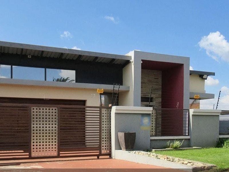 Modern front elevation featuring a contemporary facade with stone cladding, a large sliding gate, and secure electric fencing.