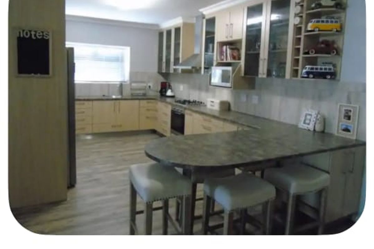A functional kitchen featuring light-toned cabinetry, laminate countertops, a breakfast bar, and integrated appliances, providing ample storage and workspace.