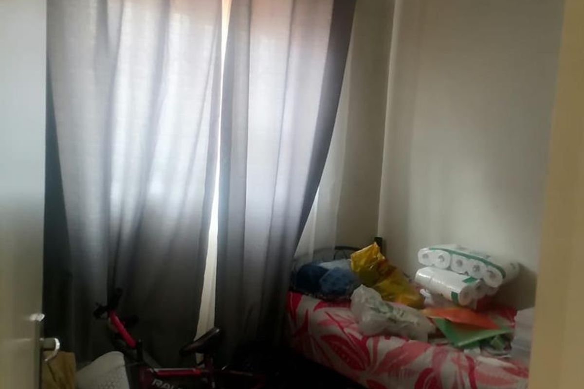 A compact bedroom featuring tiled flooring and large window curtains, offering a functional space for rest or storage.