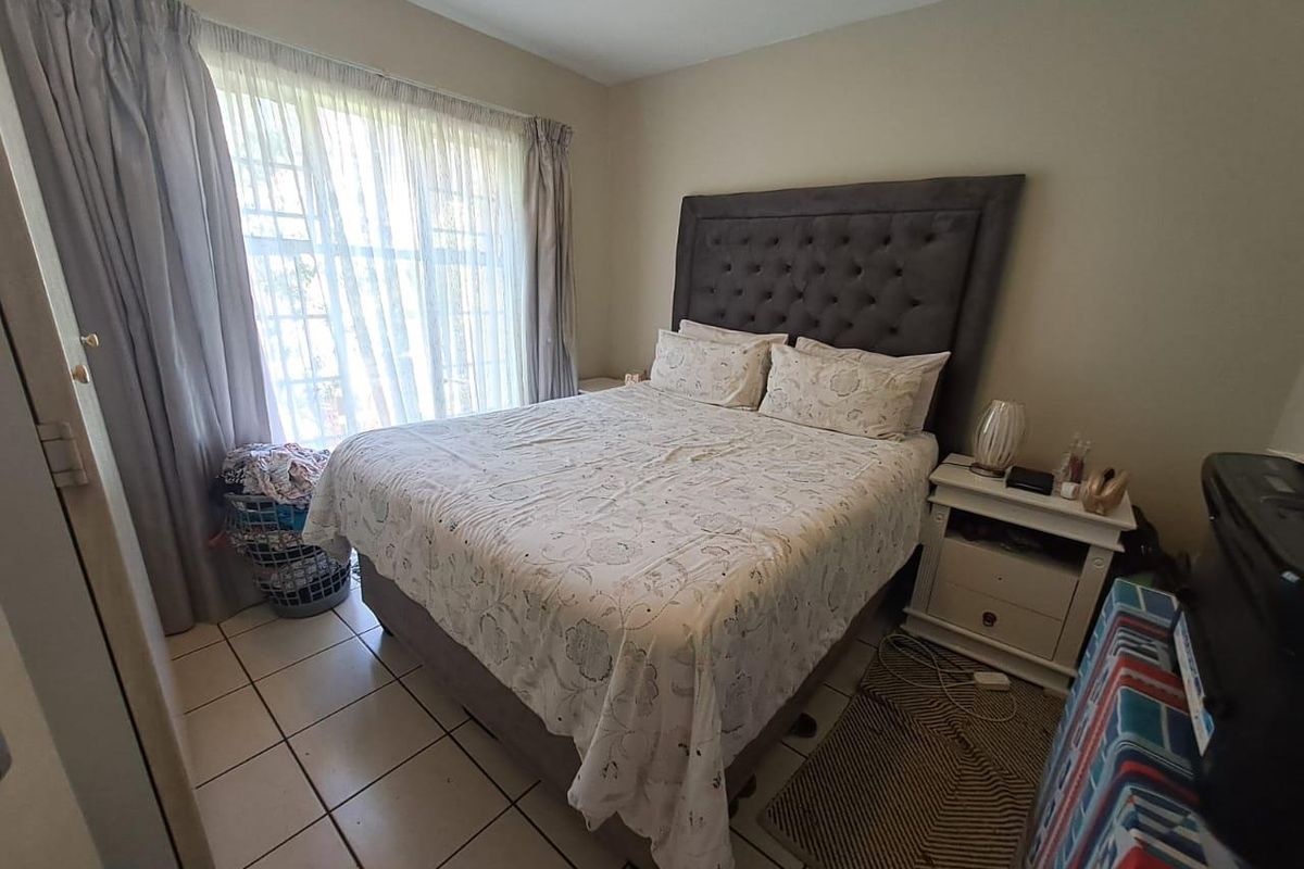 A bedroom featuring tiled flooring and a large window with curtain tracks, providing natural light and a functional layout.