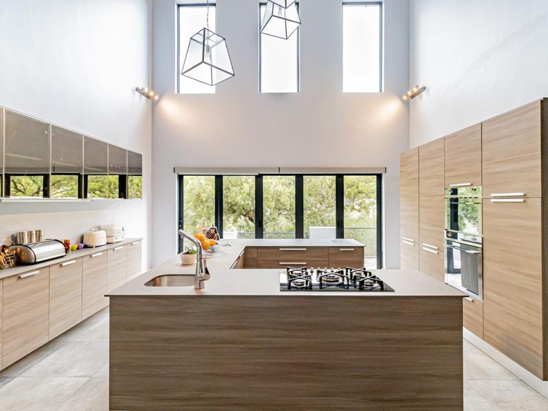 Modern, spacious kitchen featuring a large island with a gas hob, integrated cabinetry, and high ceilings with abundant natural light.