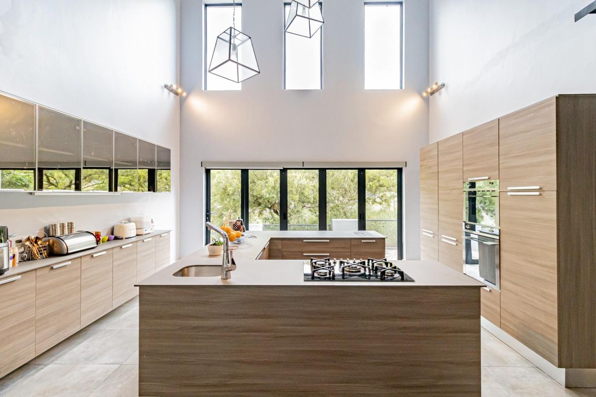 Modern, spacious kitchen featuring a large island with a gas hob, integrated cabinetry, and high ceilings with abundant natural light.
