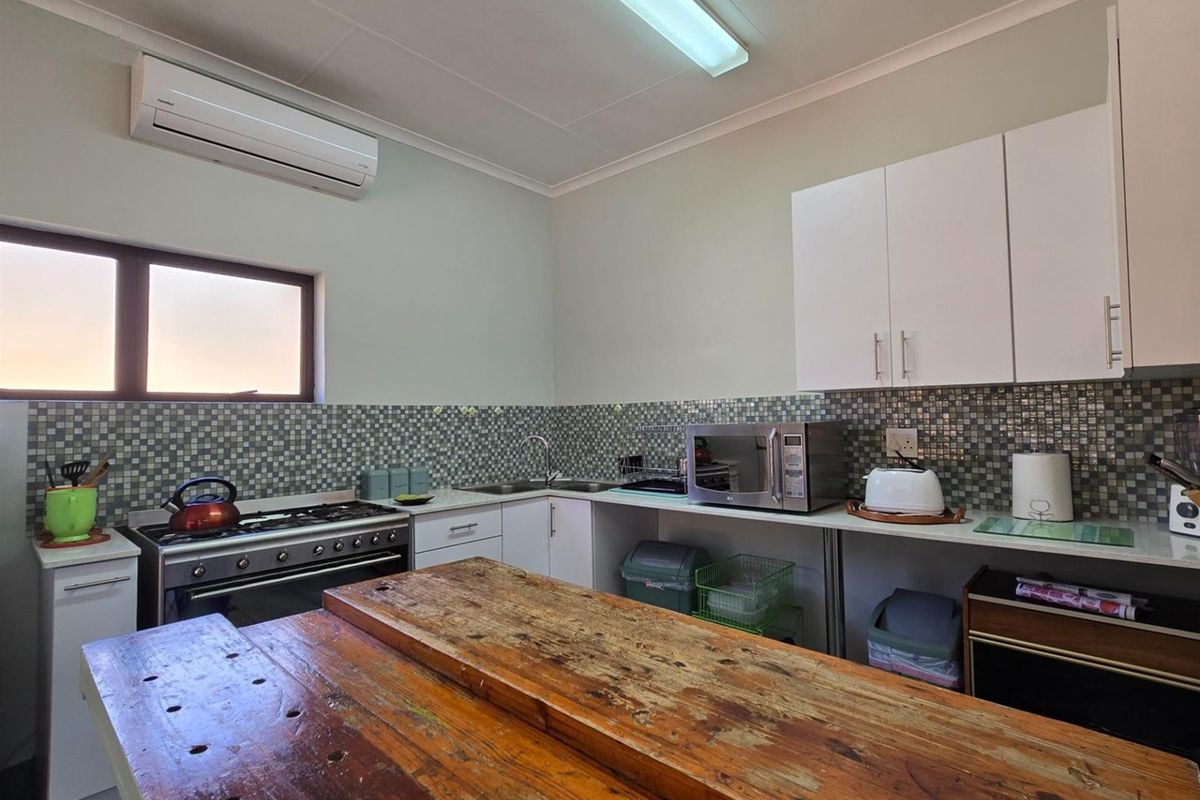 Functional kitchen featuring mosaic tile backsplash, built-in cabinetry, gas stove, and a split-system air conditioner for climate control.