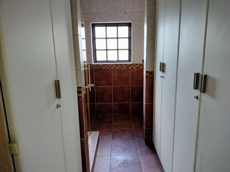 A functional bathroom space featuring built-in cupboards and tiled finishes, offering a clean and practical layout.