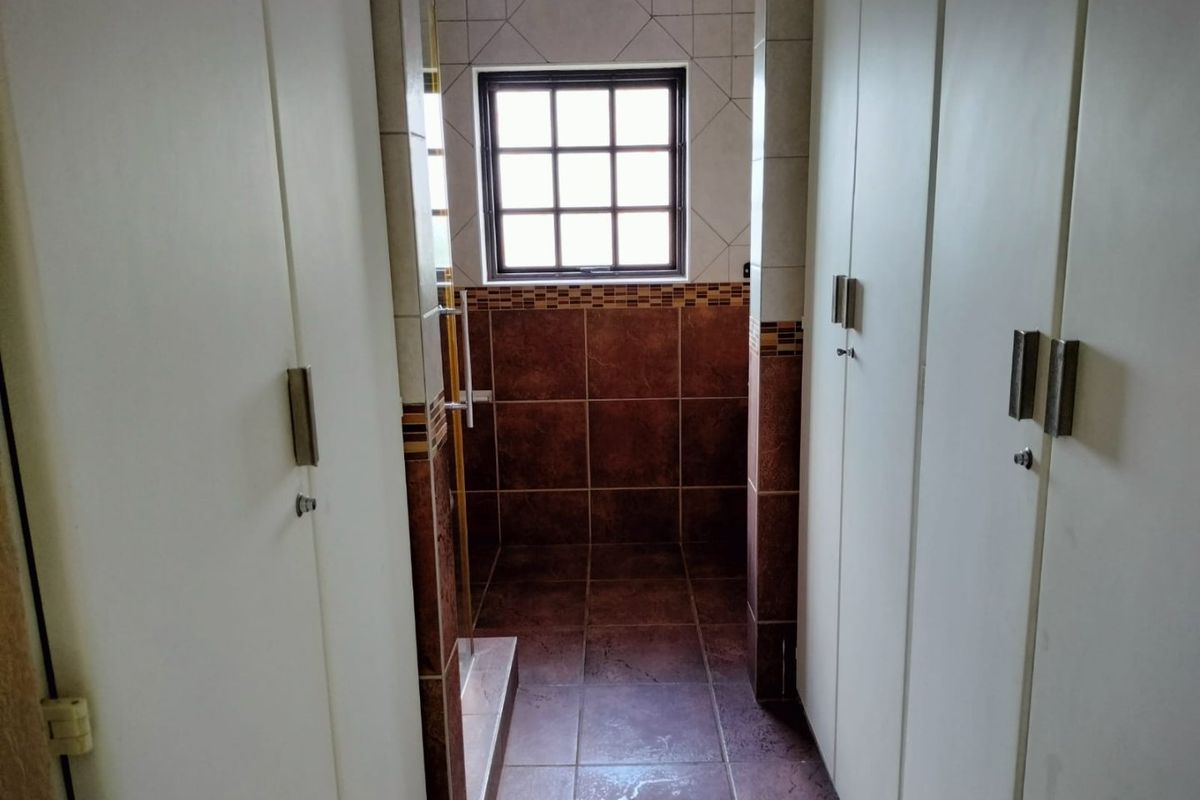 A functional bathroom space featuring built-in cupboards and tiled finishes, offering a clean and practical layout.
