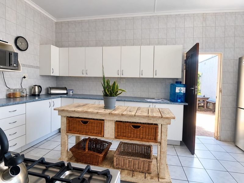 Functional kitchen featuring white cabinetry, tiled walls, and a gas hob, with direct access to an outdoor patio area.