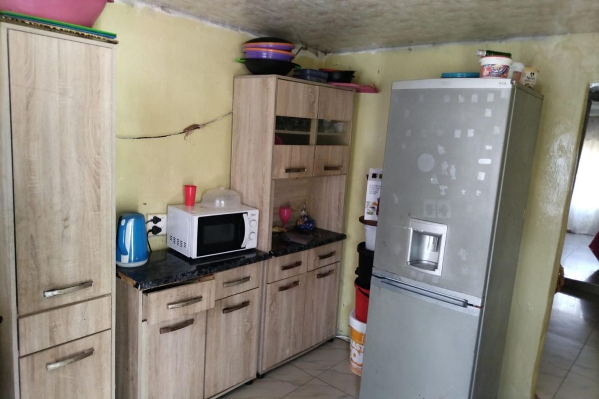 A compact kitchen area featuring laminate cabinetry and tiled flooring, currently showing signs of wear and requiring cosmetic updates to the walls and ceiling.