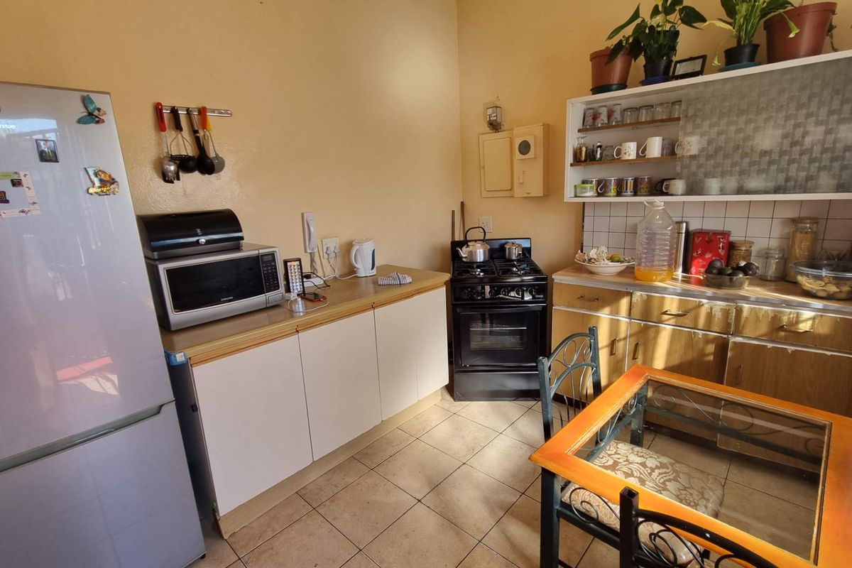 A functional kitchen featuring built-in cabinetry, a gas stove with oven, tiled flooring, and a tiled backsplash, offering a practical layout for daily cooking.