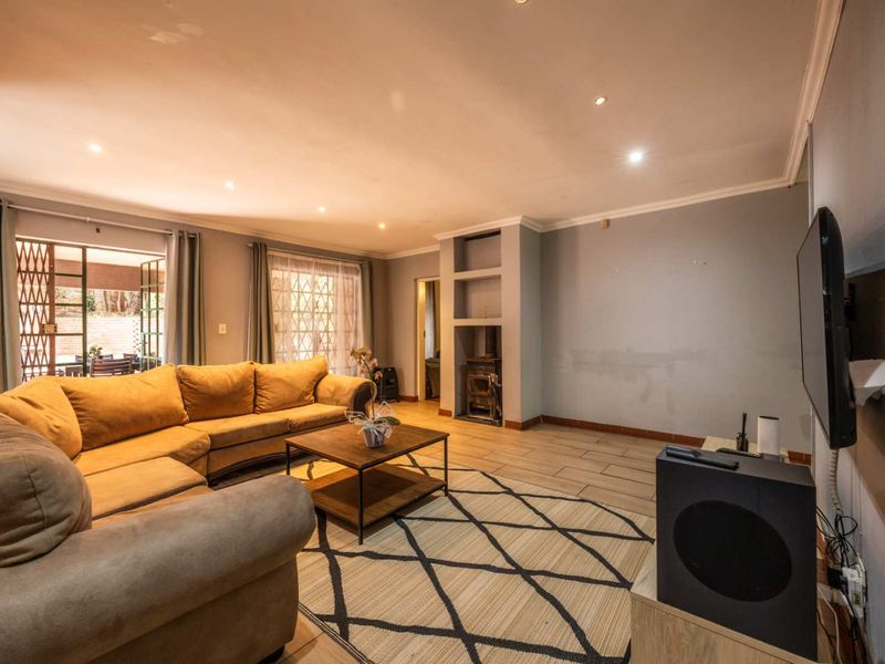Spacious living room featuring tiled floors, recessed lighting, and a built-in fireplace, with direct access to an outdoor patio area.