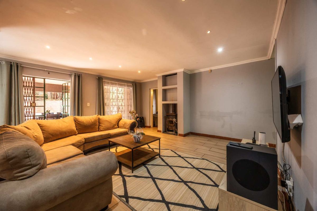 Spacious living room featuring tiled floors, recessed lighting, and a built-in fireplace, with direct access to an outdoor patio area.