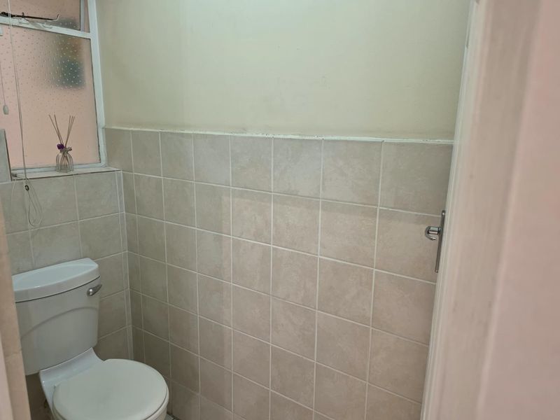 A compact bathroom featuring tiled walls and a standard toilet, requiring minor cosmetic updates to improve its overall appearance.