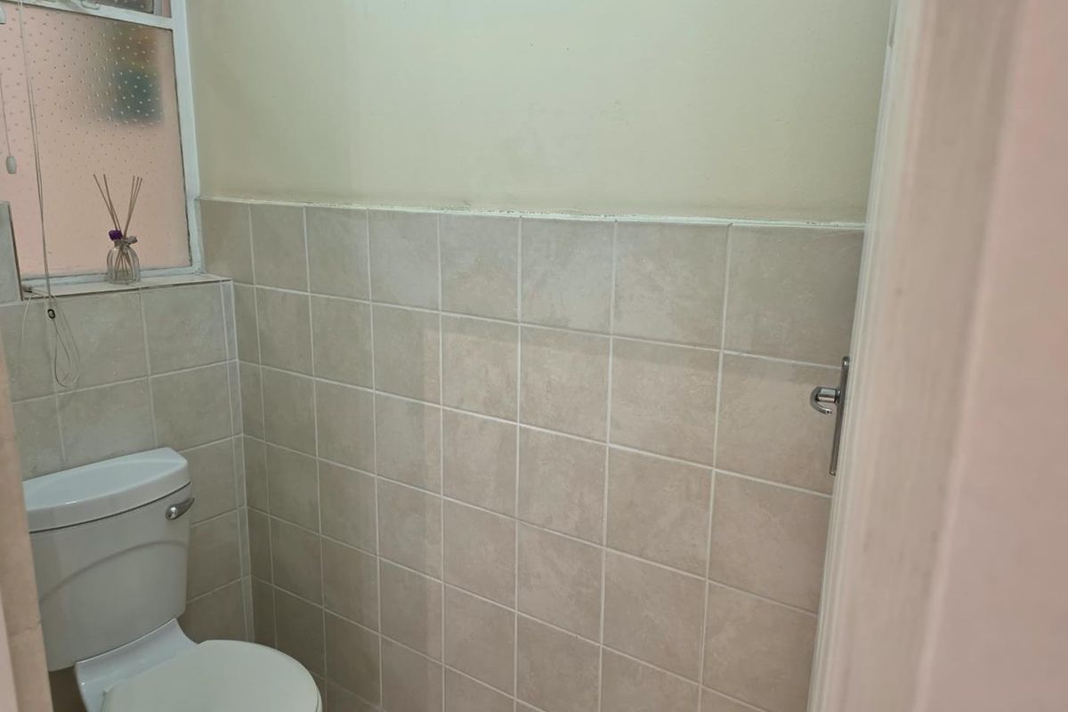 A compact bathroom featuring tiled walls and a standard toilet, requiring minor cosmetic updates to improve its overall appearance.
