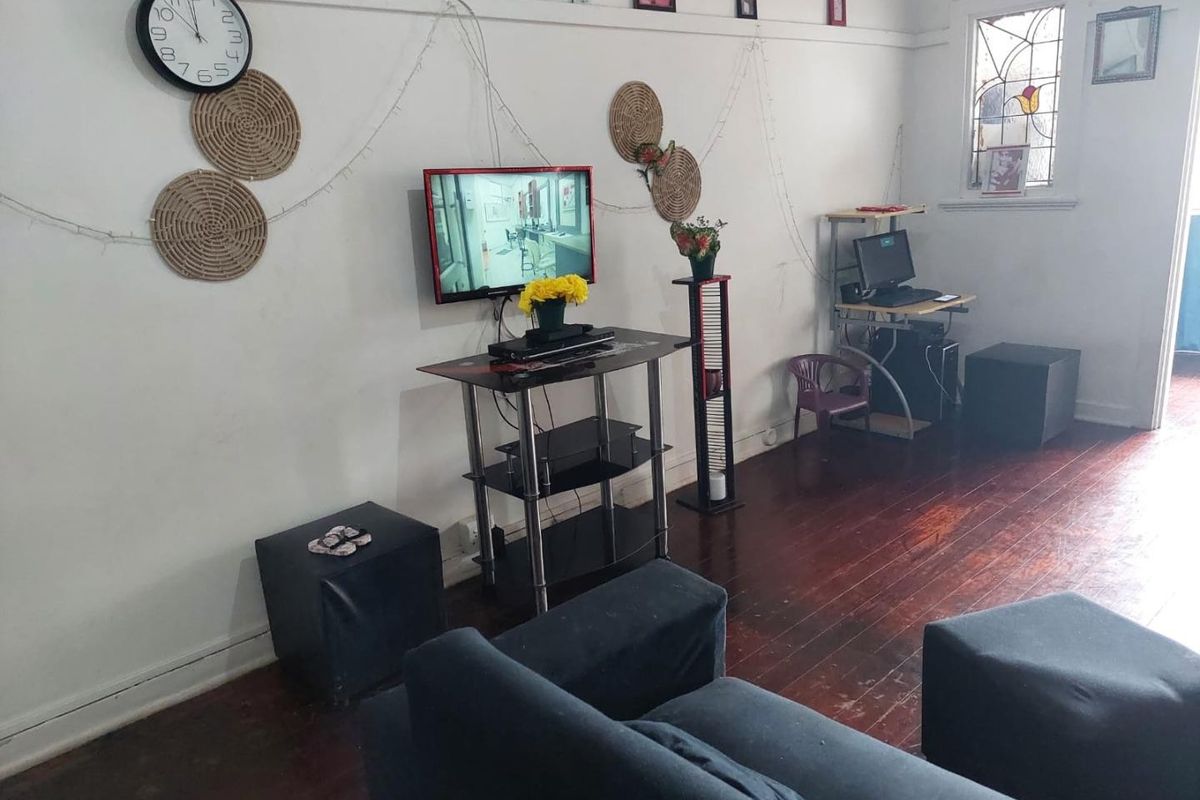 A living room featuring original timber flooring, a decorative stained glass window, and traditional picture rails, offering a character-filled space ready for modernization.