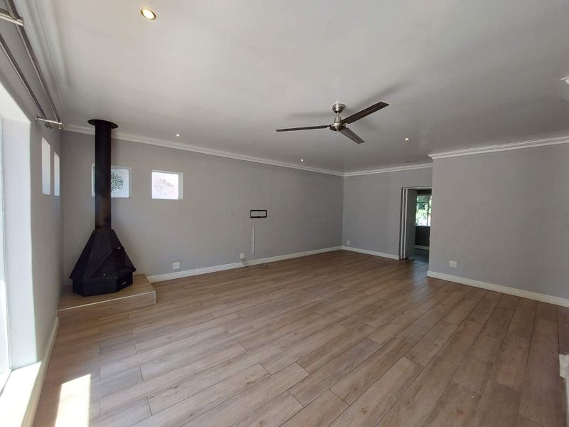 Spacious living room featuring wood-look tile flooring, a modern freestanding fireplace, ceiling fan, and recessed lighting in a neutral color palette.