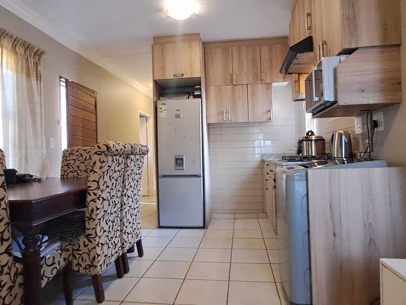 Open-plan living and kitchen area featuring tiled flooring, built-in wooden cabinetry, and a tiled backsplash, creating a functional and connected living space.