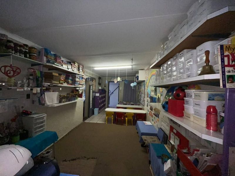 A functional utility or storage space featuring extensive built-in shelving and overhead fluorescent lighting, currently utilized for organizational purposes.