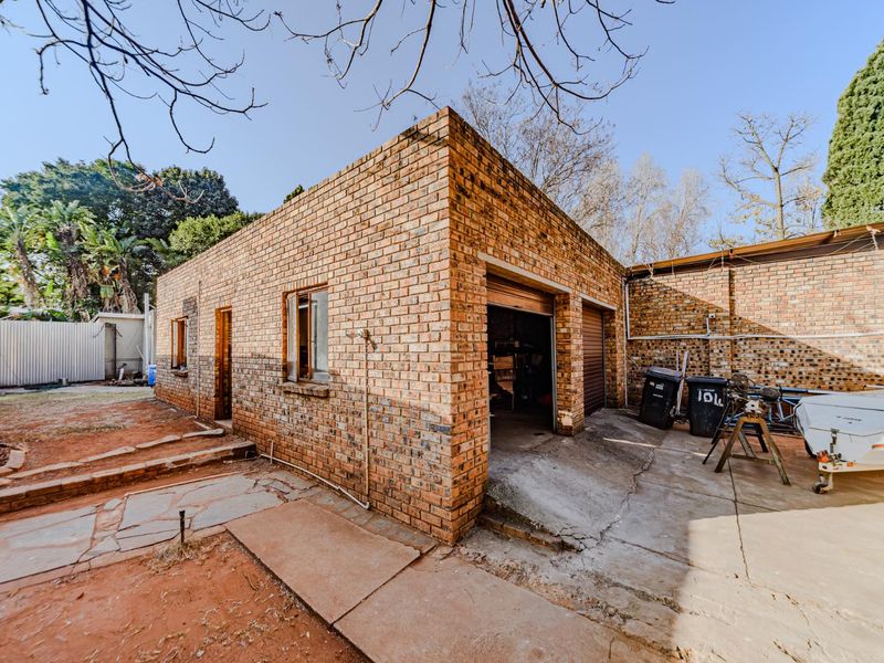 A detached face brick garage structure with roll-up doors and an adjacent concrete driveway area.