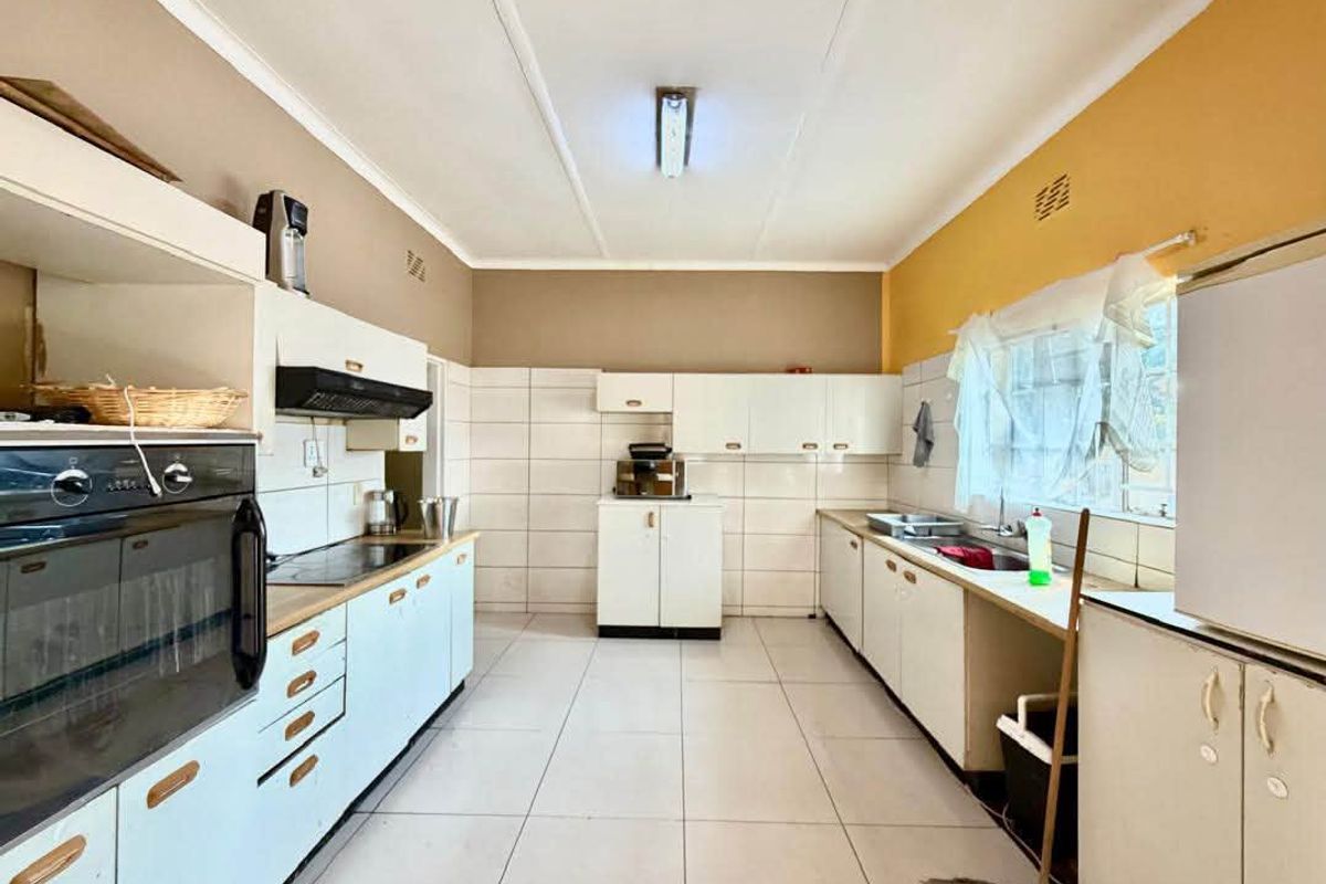 Functional kitchen featuring built-in oven, extractor fan, hob, and double sink with ample cabinetry and tiled finishes throughout.