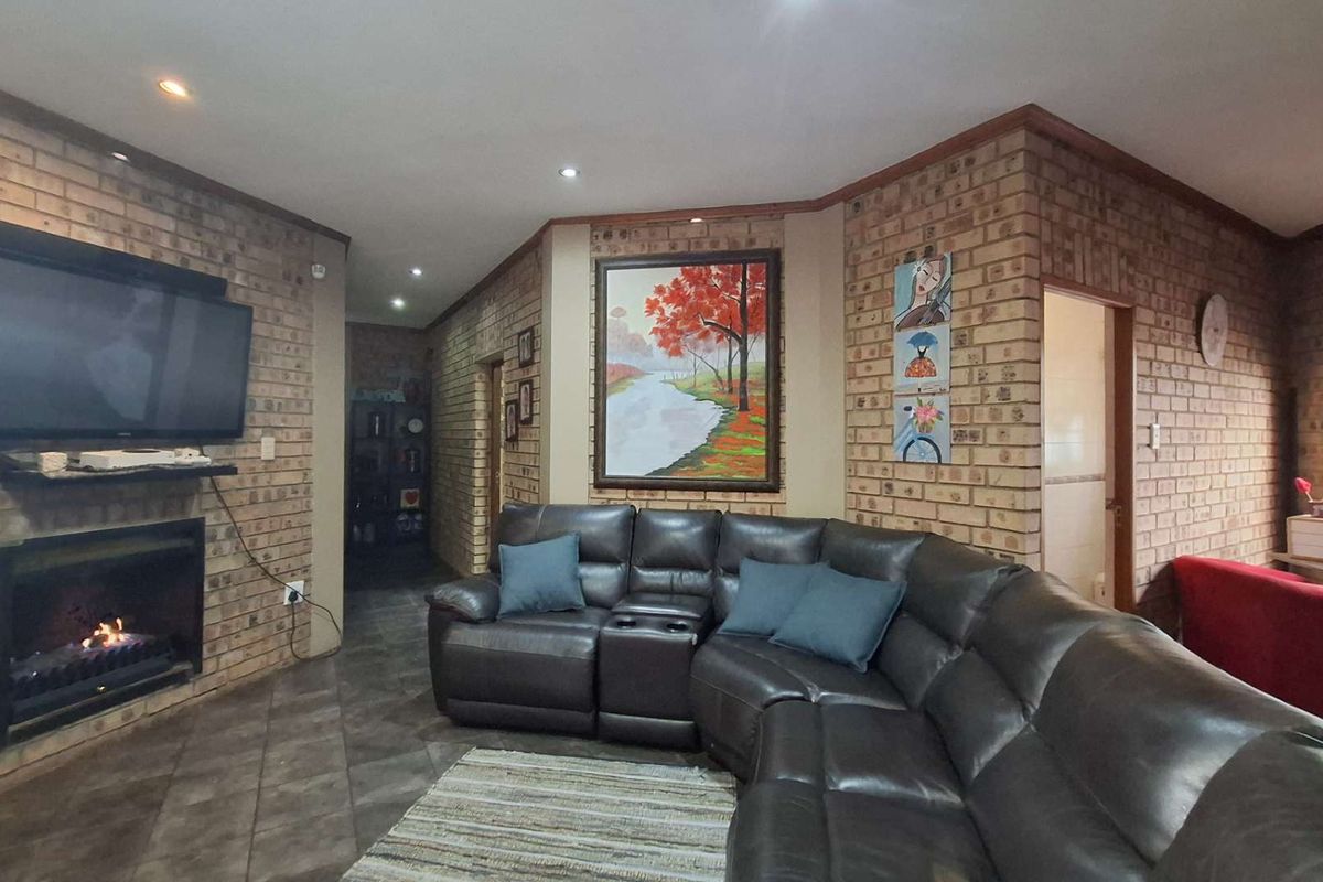 Spacious living room featuring exposed brick walls, a built-in fireplace, and tiled flooring, creating a warm and rustic atmosphere.