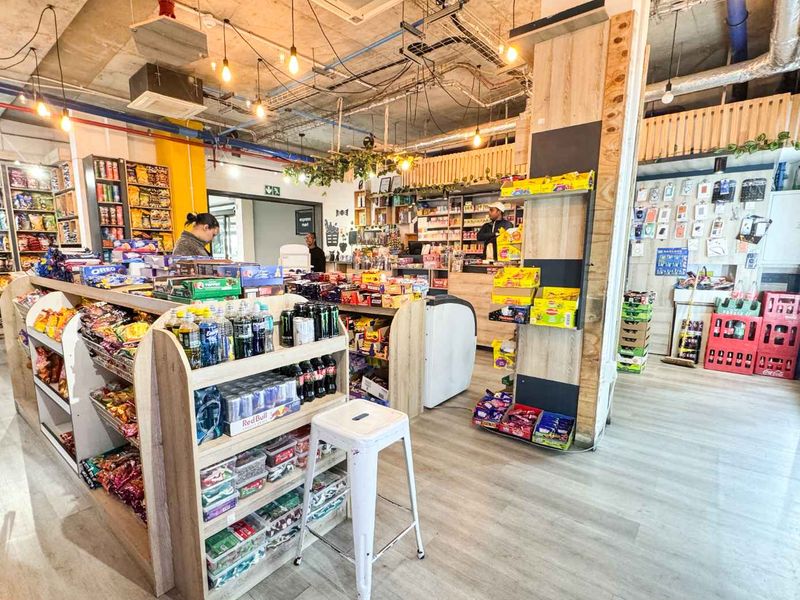 Interior view of a retail convenience store featuring exposed industrial ceiling services, laminate flooring, and integrated retail shelving units.