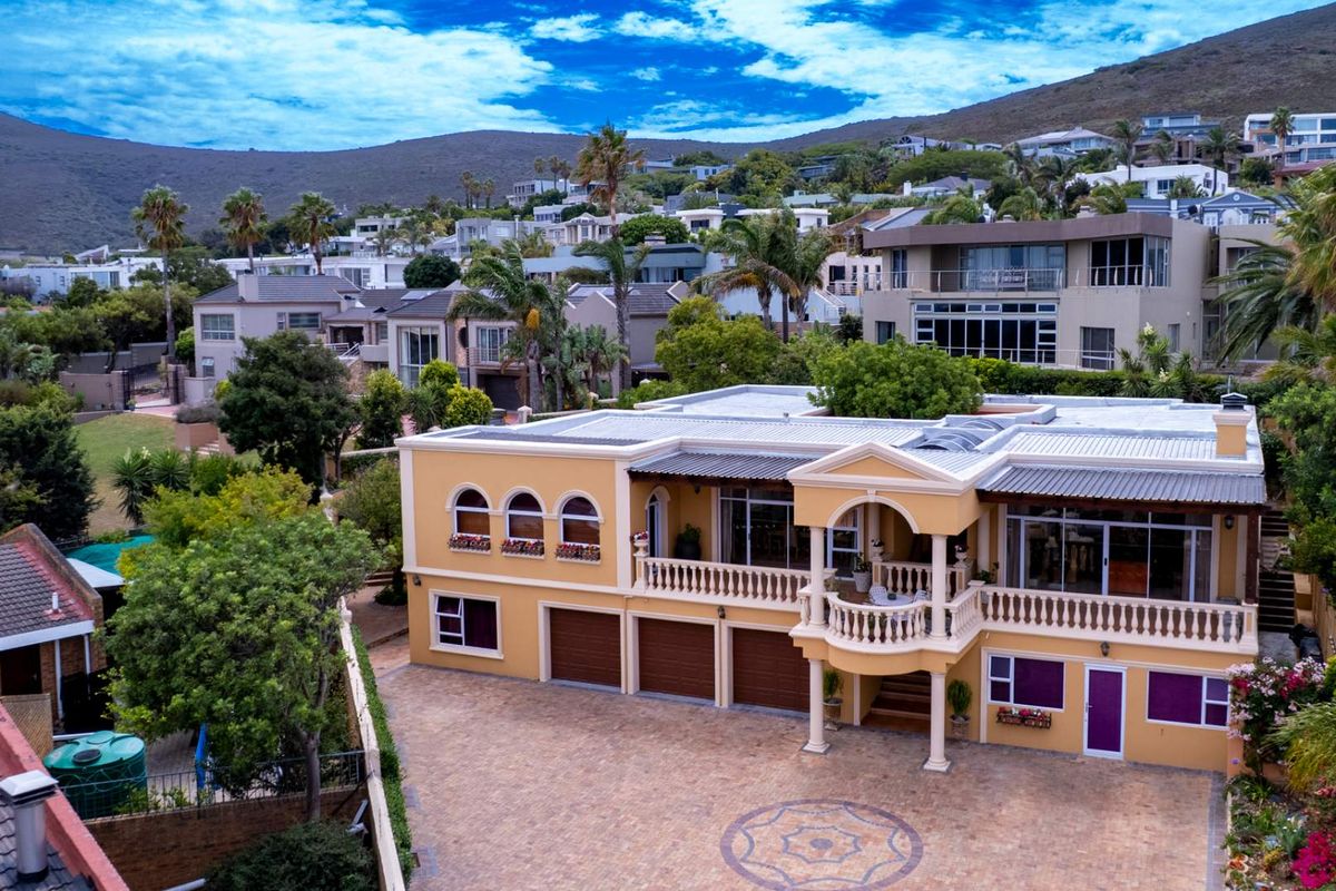 Aerial view of a Mediterranean-style residence featuring a triple garage, expansive paved driveway, and a prominent upper-level balcony with decorative balustrades.