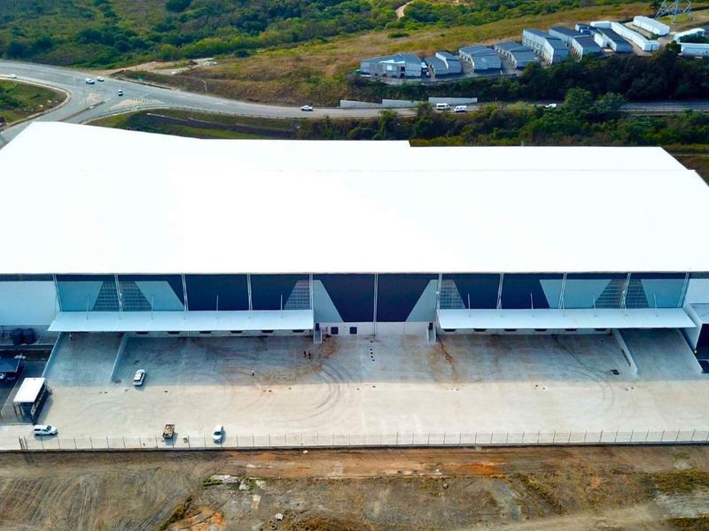 Aerial view of a modern industrial warehouse facility featuring a large-span roof, multiple loading docks, and an expansive concrete yard area.