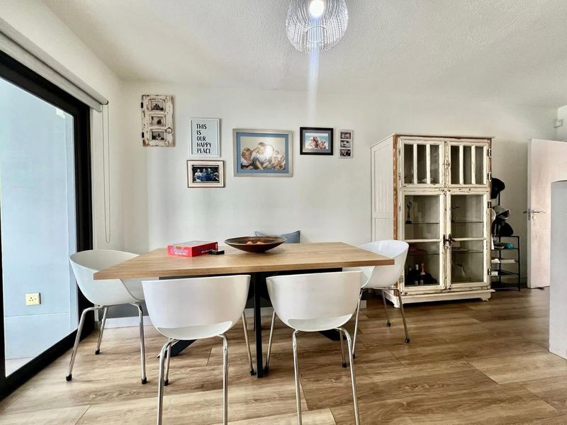 A bright dining area featuring modern laminate flooring and a large sliding glass door providing access to the outdoor space.