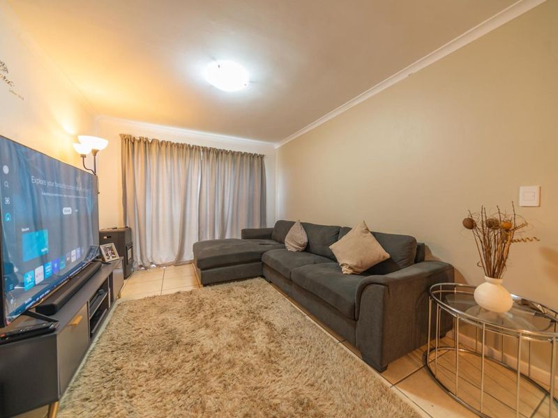 A comfortable living room featuring tiled flooring, cove cornicing, and a sliding door leading to an outdoor area.
