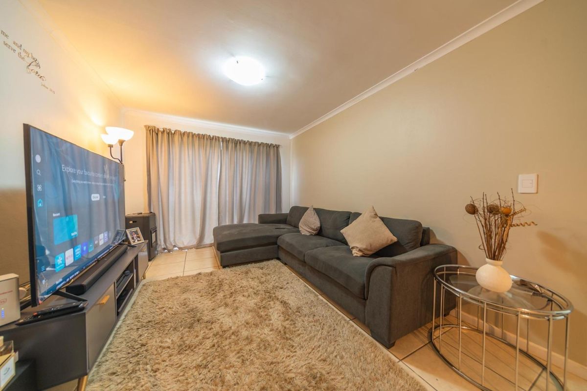 A comfortable living room featuring tiled flooring, cove cornicing, and a sliding door leading to an outdoor area.