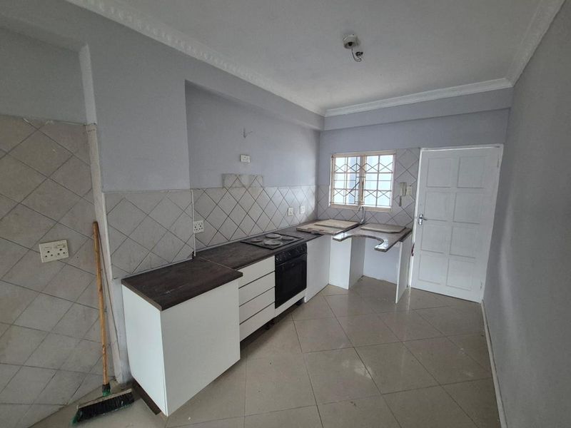 A compact kitchen featuring built-in cabinetry, an oven and hob, and tiled flooring. The space requires minor finishing and updates to reach its full potential.