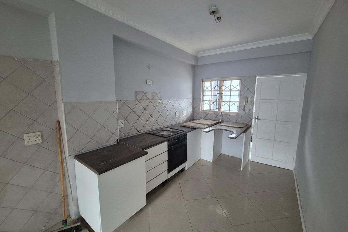 A compact kitchen featuring built-in cabinetry, an oven and hob, and tiled flooring. The space requires minor finishing and updates to reach its full potential.