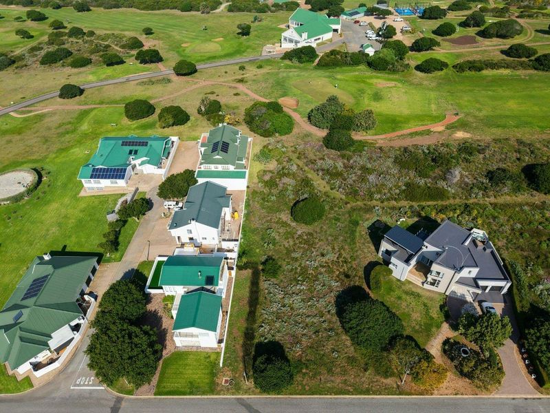 Aerial view of a vacant residential plot situated within a golf estate, featuring surrounding homes and established landscaping.