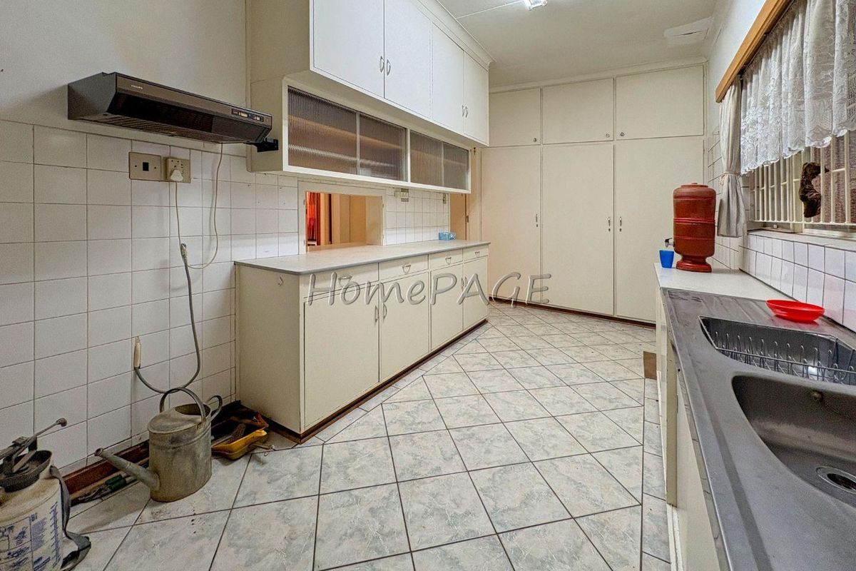 A functional kitchen featuring built-in cabinetry, tiled splashbacks, and a double sink, offering a practical layout with ample storage space.