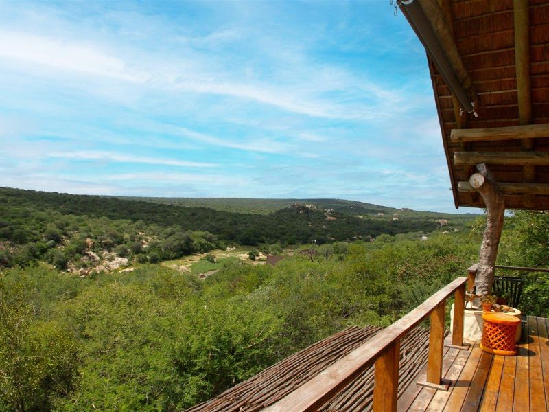 A wooden balcony featuring timber decking and a rustic balustrade, offering expansive views over the surrounding natural landscape.