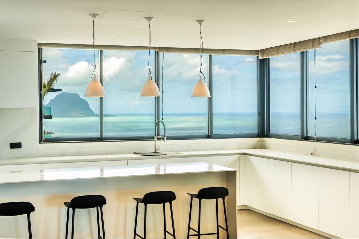 Modern kitchen featuring sleek white cabinetry, stone countertops, and a breakfast bar, perfectly positioned to enjoy expansive ocean and mountain views.
