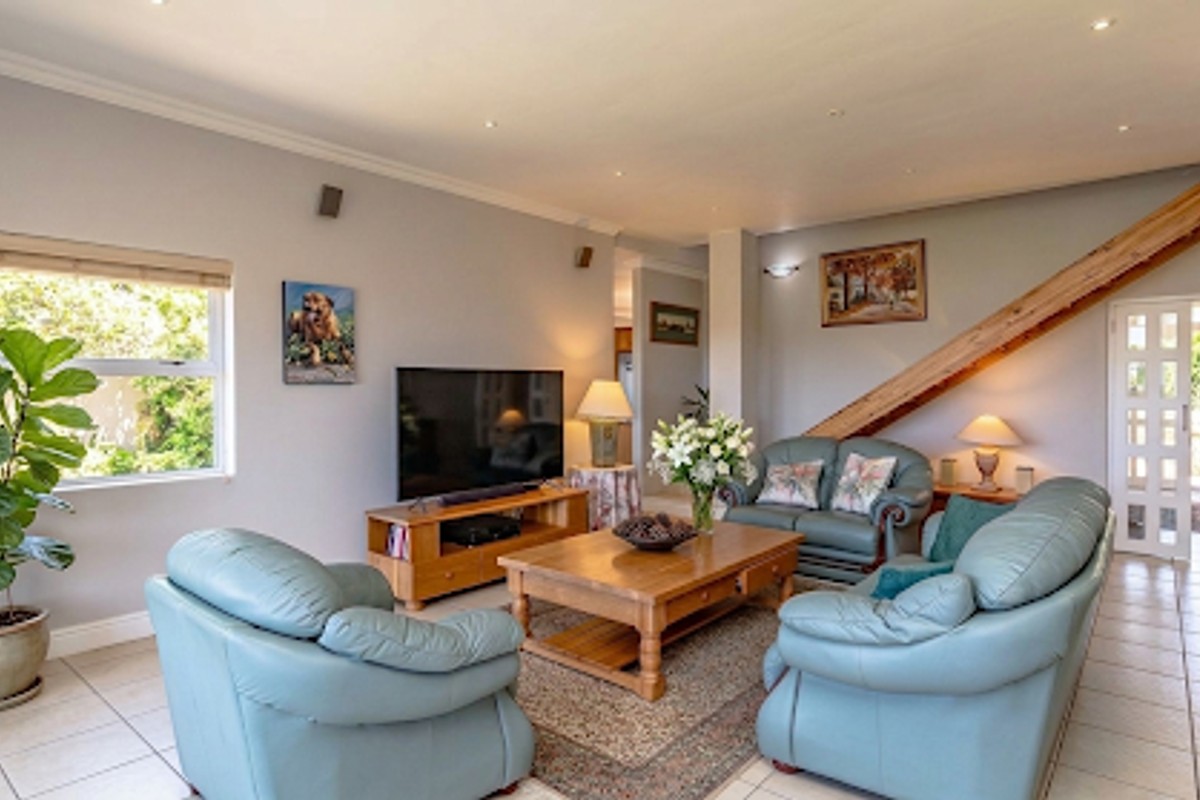 Spacious living room featuring tiled flooring, recessed downlighting, and a wooden staircase leading to the upper level.