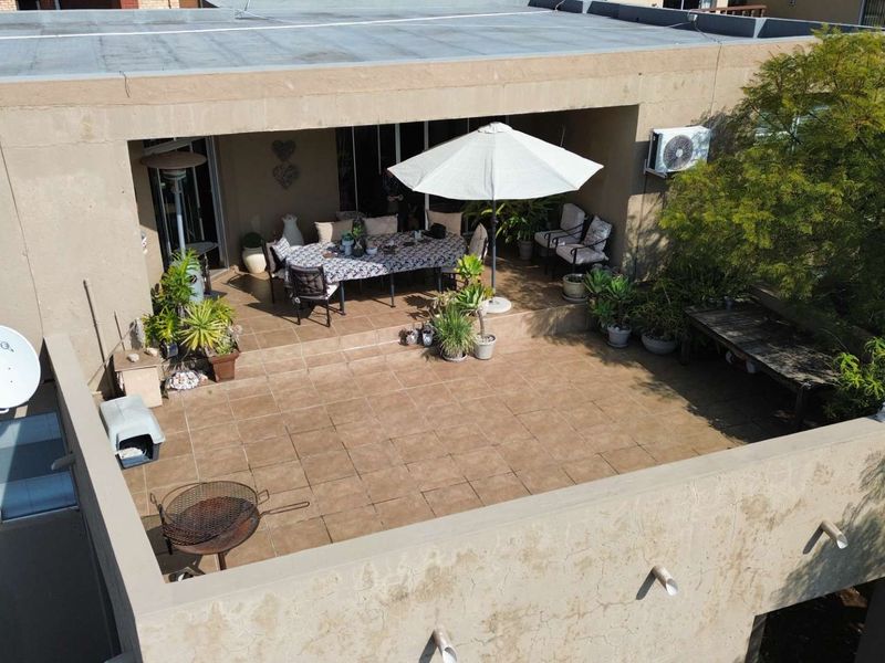 Spacious elevated patio area featuring tiled flooring, built-in lighting, and an integrated air conditioning unit, offering a functional outdoor entertainment space.