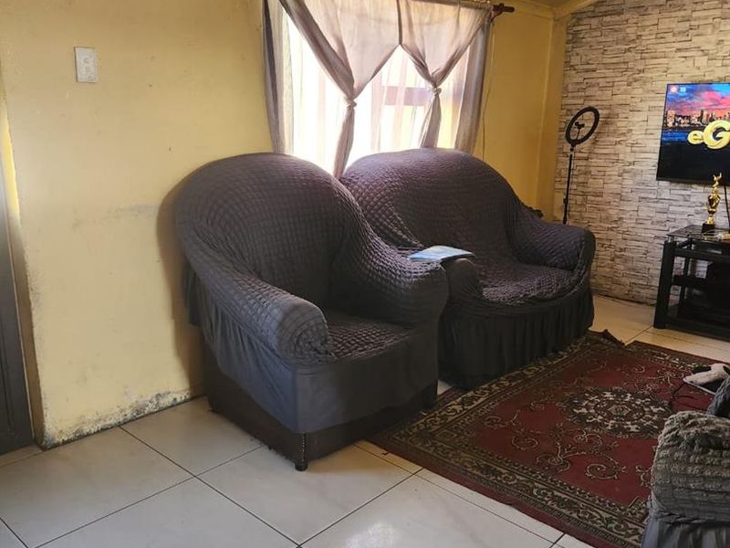 Living room featuring tiled flooring and a faux brick accent wall, requiring cosmetic updates to the wall finishes.