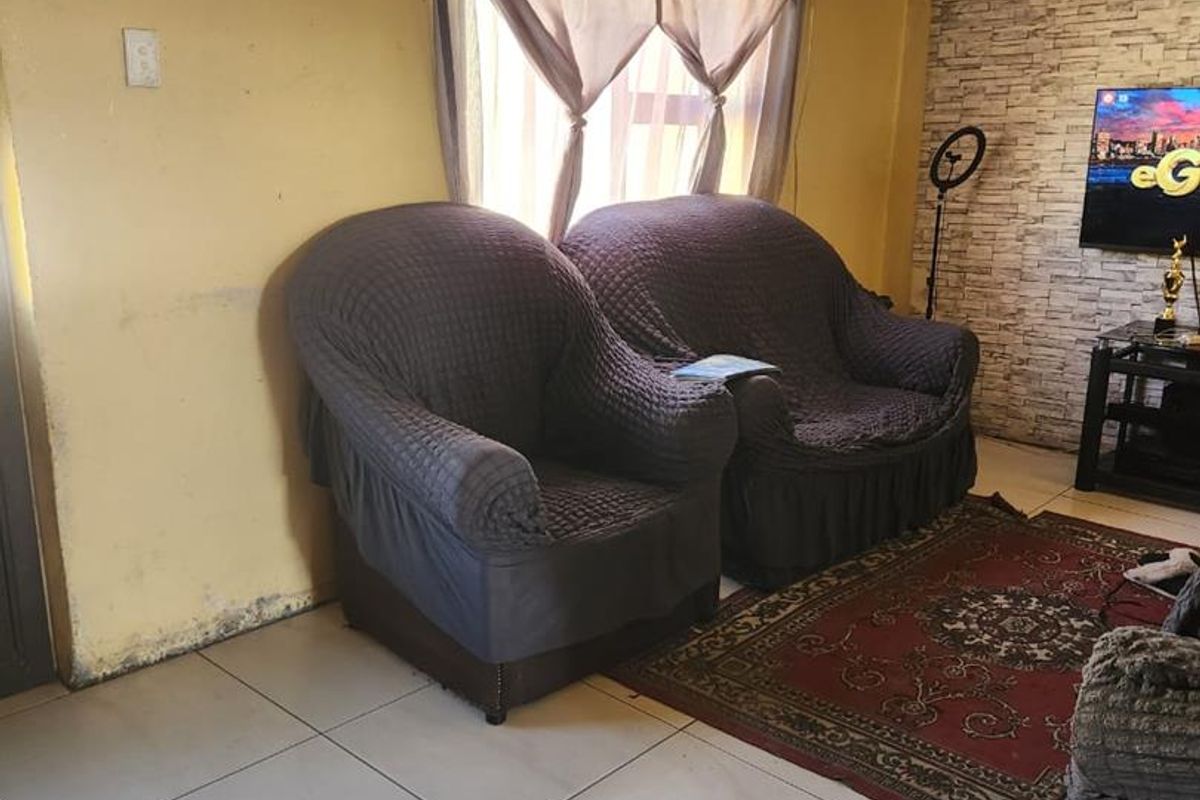 Living room featuring tiled flooring and a faux brick accent wall, requiring cosmetic updates to the wall finishes.
