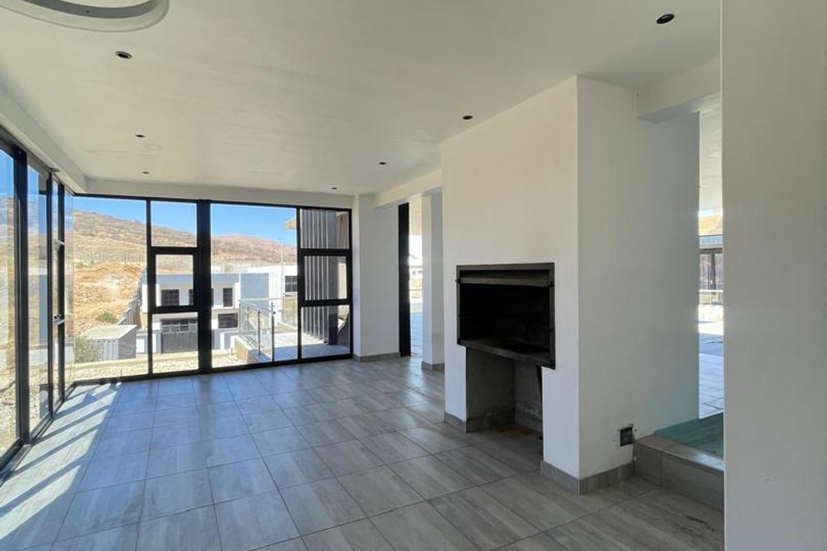 Spacious, modern living area featuring large glass sliding doors, tiled flooring, and a built-in fireplace, offering a bright and open atmosphere.