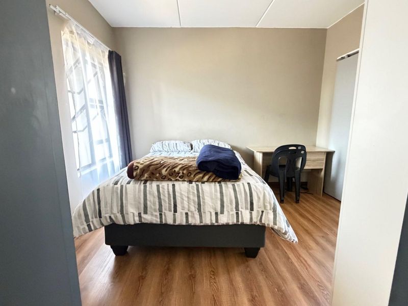 A functional bedroom featuring laminate flooring and a built-in cupboard, offering a neutral space ready for personalization.