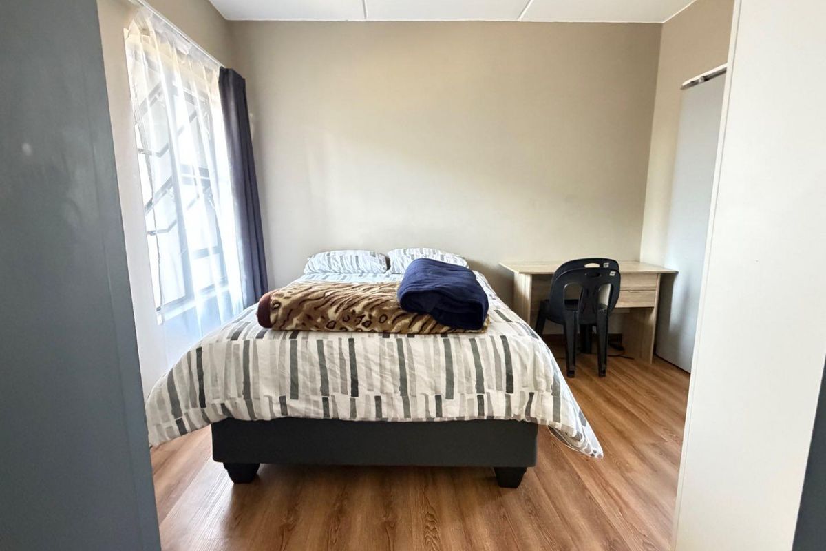 A functional bedroom featuring laminate flooring and a built-in cupboard, offering a neutral space ready for personalization.
