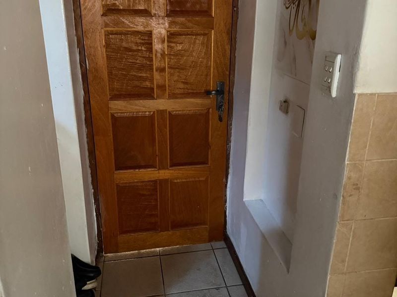A functional entry area featuring tiled flooring, a classic wooden panel door, and a recessed wall niche.