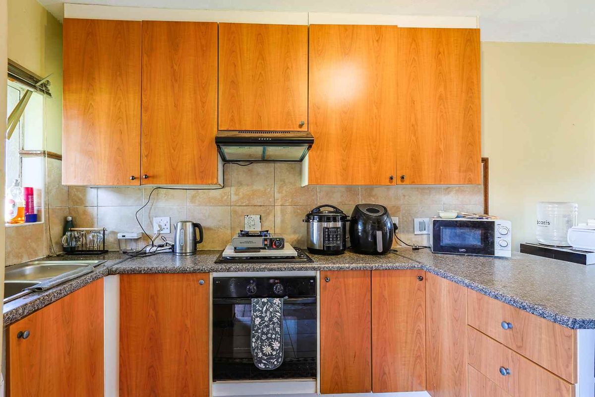 A functional kitchen featuring wood-finish cabinetry, granite-look countertops, a built-in oven, and an extractor fan.