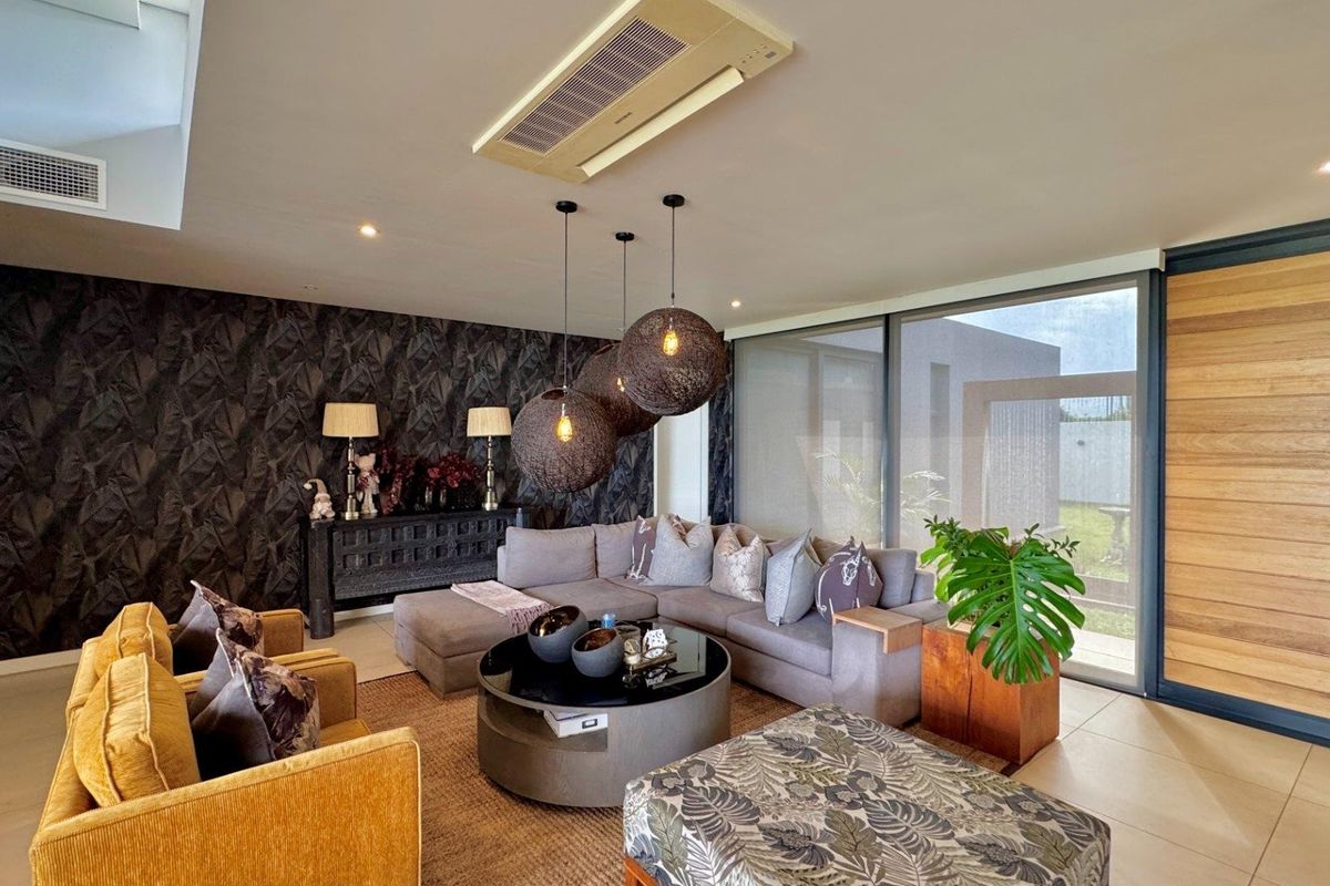 Modern living room featuring ducted air conditioning, feature wallpaper, and large sliding glass doors providing seamless access to the outdoor area.