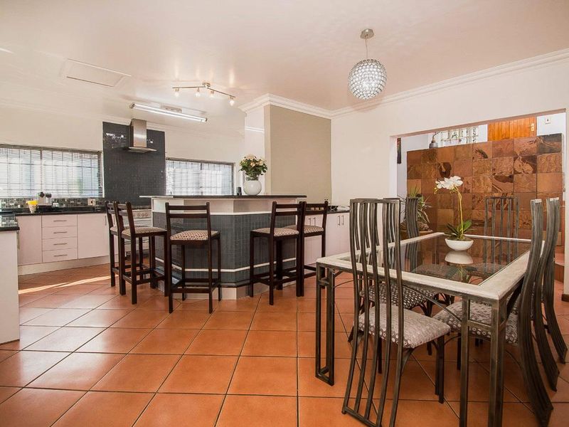 Open-plan kitchen and dining area featuring a central island, tiled flooring, and decorative stone wall cladding.