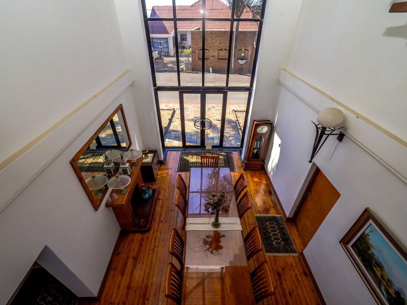Spacious dining area featuring double-height windows, hardwood flooring, and a fireplace, creating an airy and elegant atmosphere.
